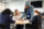 Waist-up view of 15 and 16 year old classmates in uniforms sitting at round table taking notes and discussing ideas.
